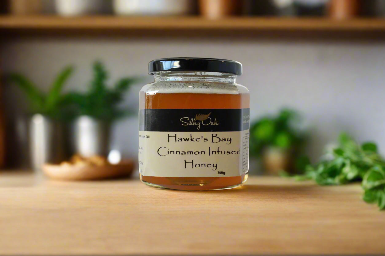 Jar of Hawke's Bay Cinnamon Infused Honey on a kitchen counter with cinnamon sticks.